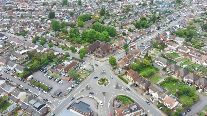Aerial view of an English suburb of semi-detached houses with tiled roofs set around a roundabout