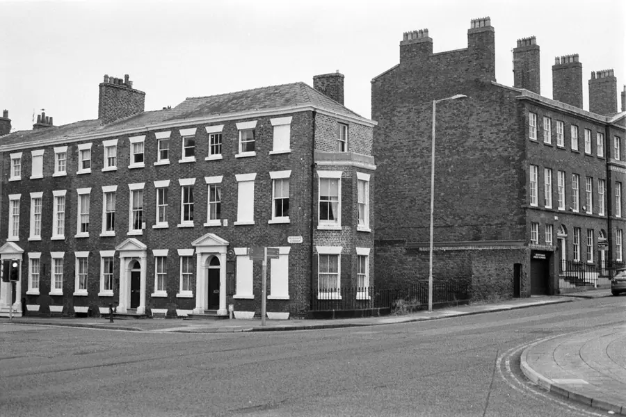 Black and white photo of brick terraced houses with tall chimney stacks, typical of the roofs Dartford roofers quote for