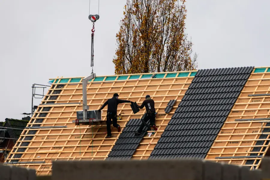Roofers fixing new grey concrete tiles over fresh timber battens and membrane, the core items a full re-roof quote in Dartford should itemise