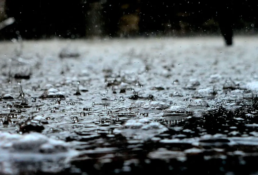 Heavy rain splashing into a puddle on the ground, the weather that pushes permanent roof repairs back to a dry spell