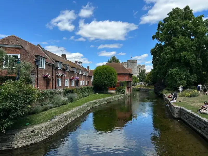 Row of red-brick cottages with steep clay tiled roofs beside a river in Kent