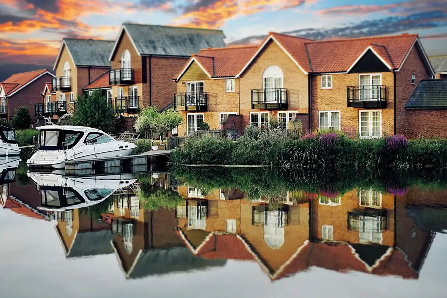 Riverside new-build brick houses with tiled roofs and balconies, the kind of 2000s development now past its NHBC warranty