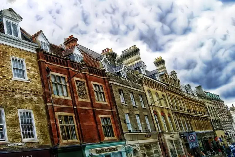 Row of old brick terraced buildings with shops below and chimney stacks running along the roofline