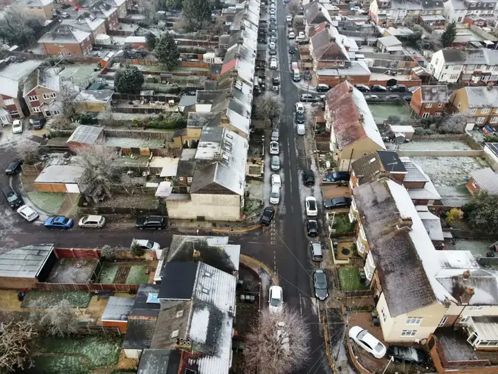 Aerial view of a terraced street with snow lying on the roofs and rear outriggers, the house type that carries most older slate roofs