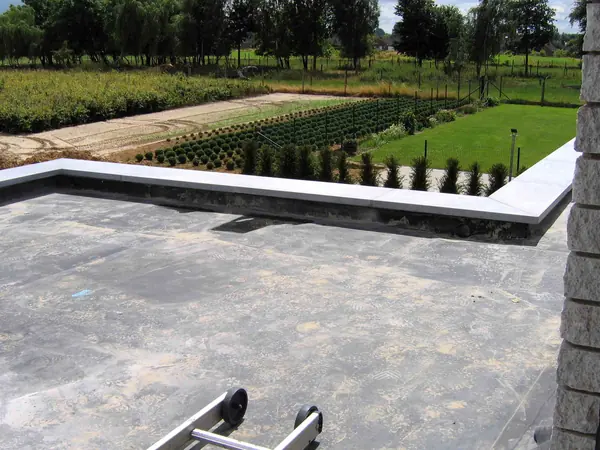 Newly finished EPDM rubber flat roof in one dark sheet, turned up under the coping stones at the edges