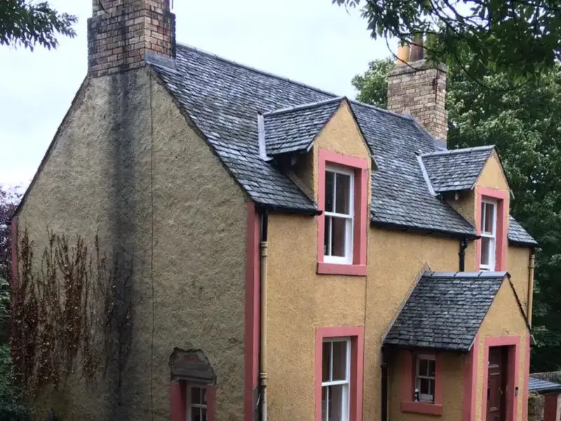 Rendered cottage with a newly laid natural slate roof, two slated dormers, a slated porch and brick chimney stacks