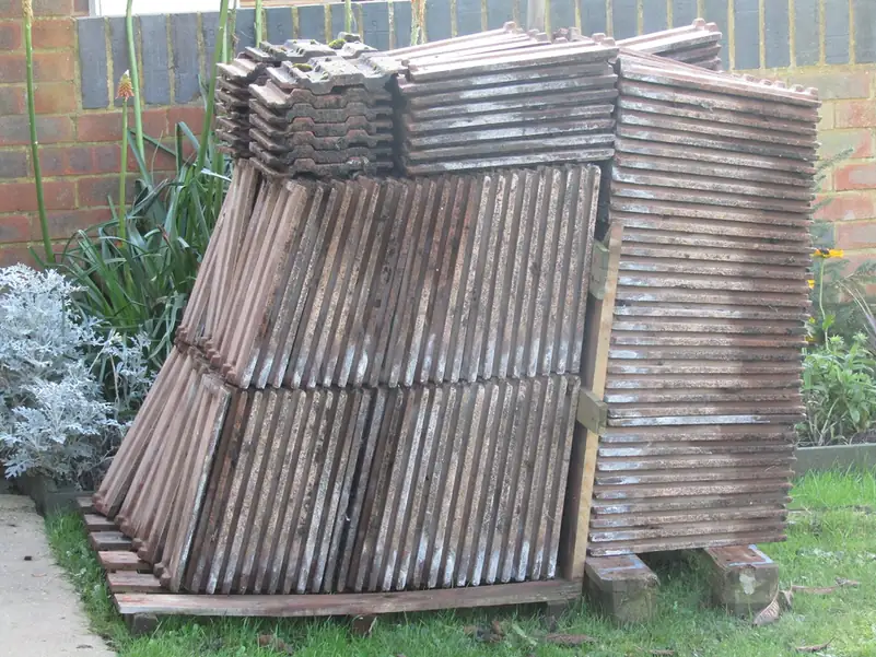 Stacks of interlocking concrete roof tiles on a pallet in a back garden, ready for re-use