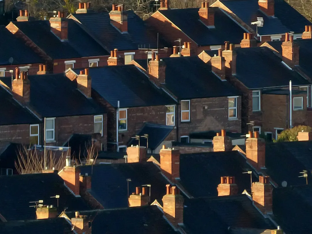 Rows of slate-roofed terraced houses with brick chimney stacks catching low evening sun